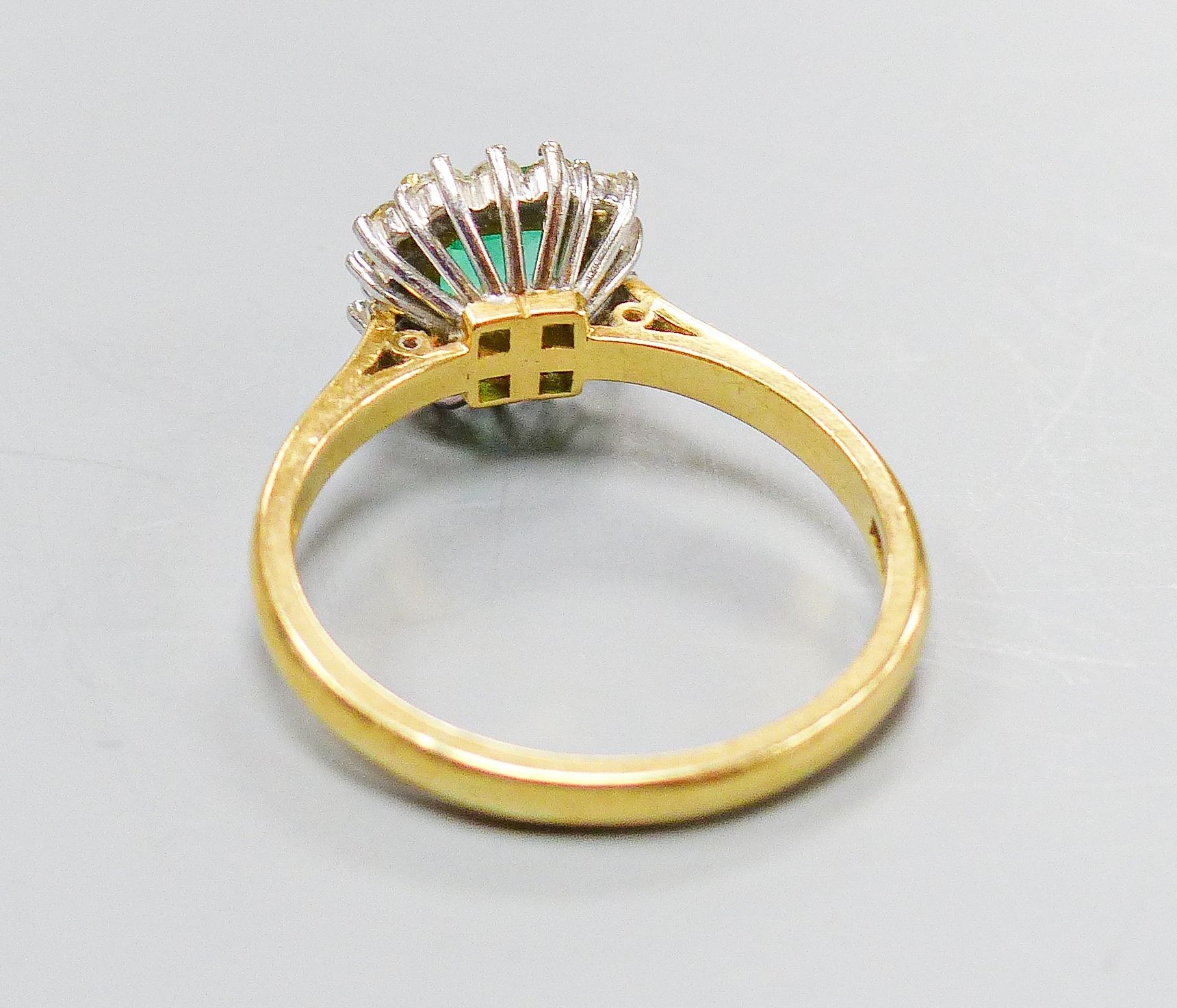 A modern 18ct gold, emerald and diamond set square cluster ring, size O, gross weight 4.3 grams.